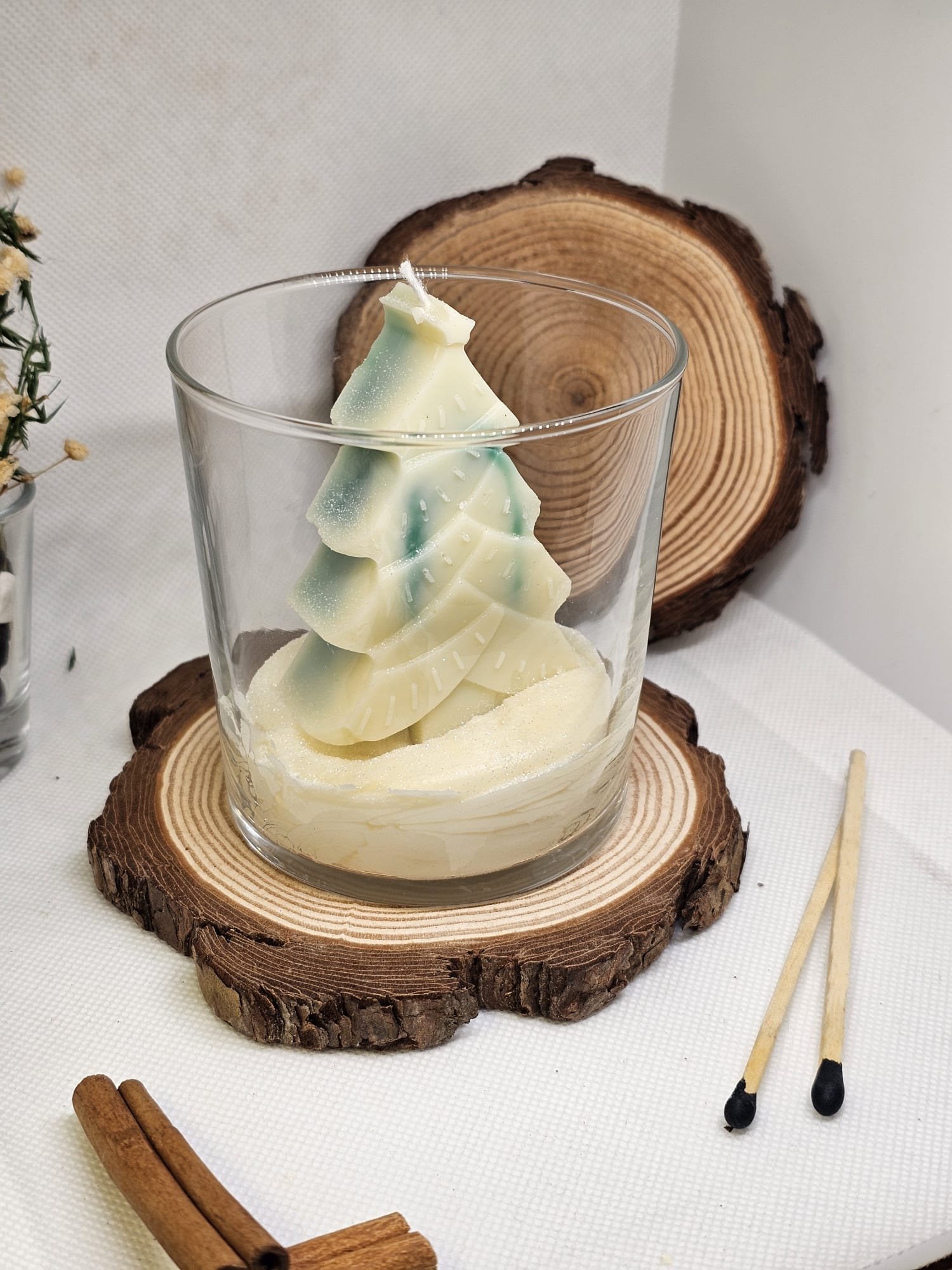 Close-up of handmade soy wax candle with layered Christmas tree inside glass container