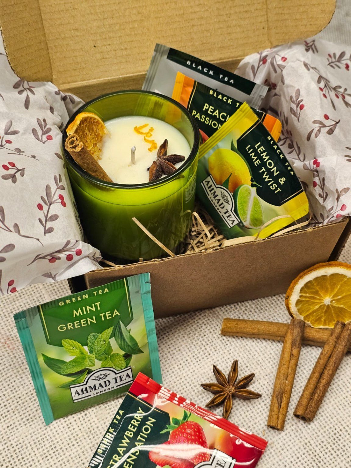 MysticGlow candle and tea gift set featuring a handmade soy wax candle in a green glass jar, five assorted Ahmad Tea bags and rustic kraft gift packaging.