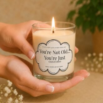 MysticGlow handmade soy wax funny birthday candle with You're Not Old You're Just Limited Edition label, burning while held in hands.